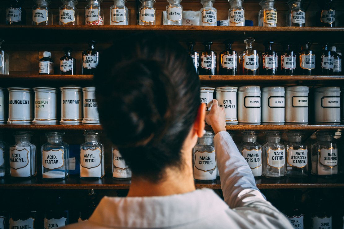 Apothekerin in der Apotheke vor einem Regal mit Flaschen und Dosen